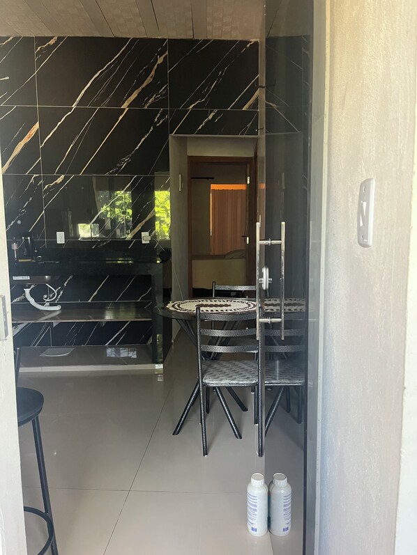 A room with a glass partition, a dining table with chairs, and two bottles on the floor.