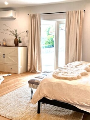 A bedroom with a bed, a dresser, and a window with curtains.