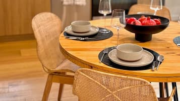 A modern kitchen with wooden cabinets, a microwave, and a stove. There is a dining table with chairs and a bowl of fruit.