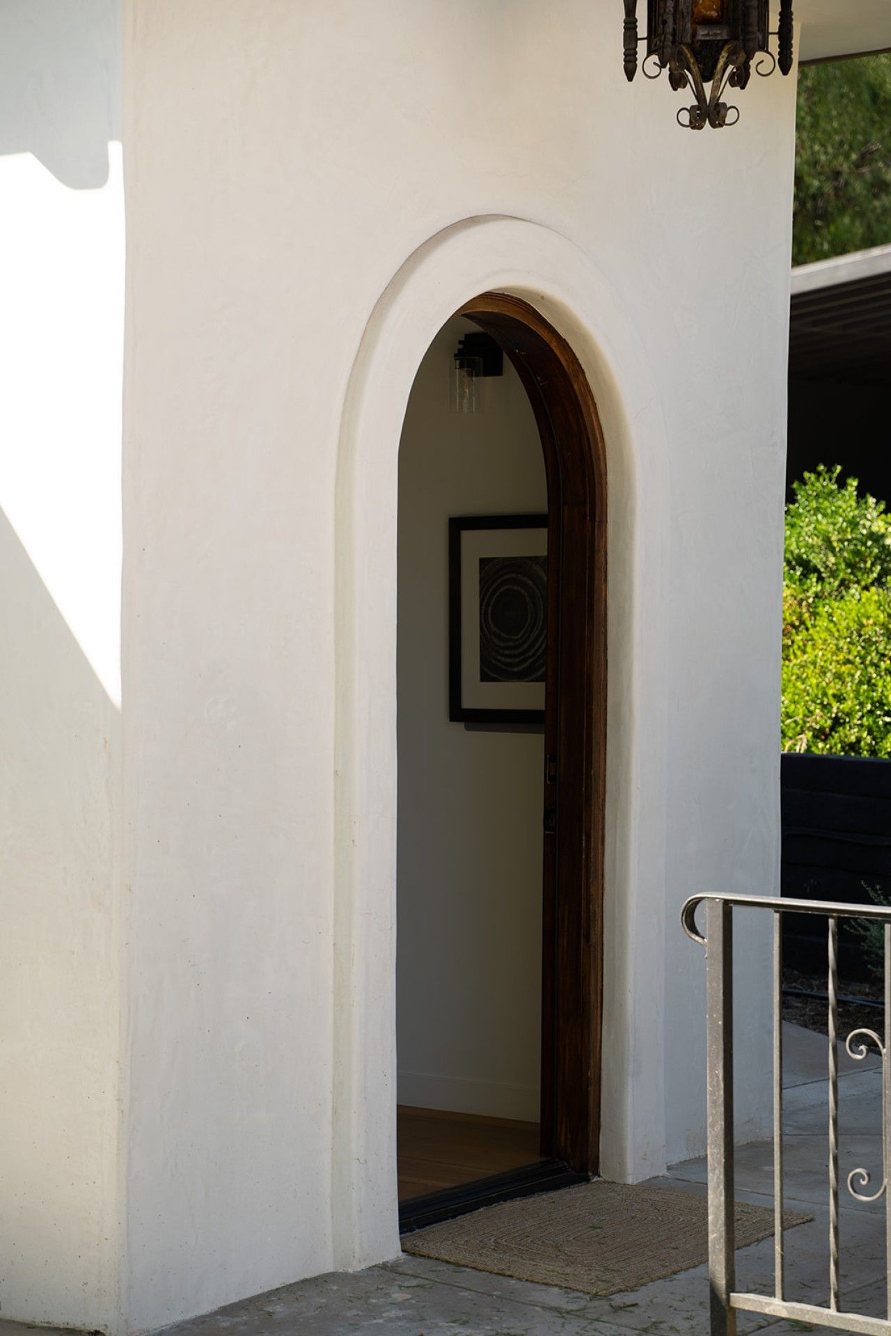 An arched doorway leading to a room with a framed picture on the wall.