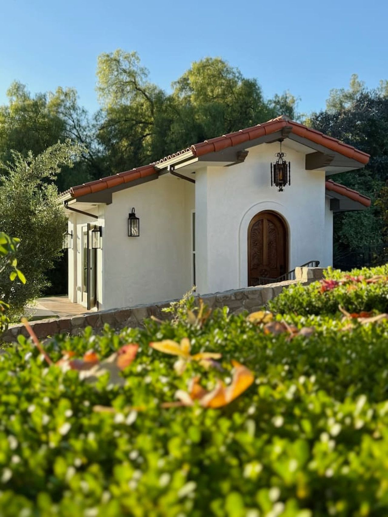 A small, single-story building with a white exterior, a red-tiled roof, and a wooden door.