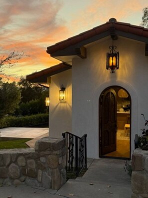 A house with a stone entrance, a wooden door, and a stone wall.
