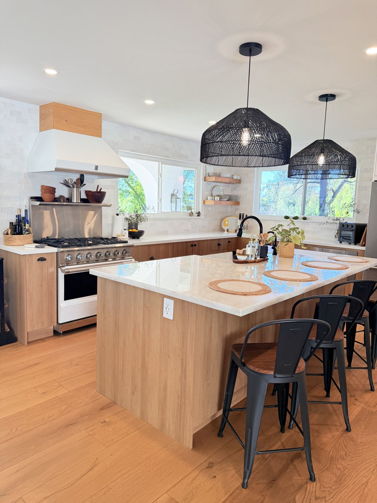 A modern kitchen with a central island, wooden cabinetry, a built-in oven, and pendant lighting.