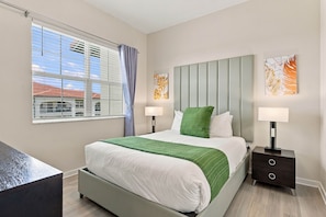 A modern bedroom with a bed, nightstands, a desk, and artwork on the walls. - Spacious 3BR, Top Location Near Parks & Convention (Orlando)