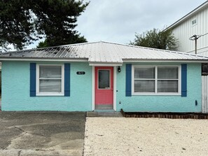 Ein eingeschossiges Haus mit roter Tür, Hausnummer 423, und einer kleinen Veranda.