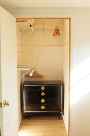 Um closet amplo com cômoda de madeira, cabideiro e varal instalado no teto.