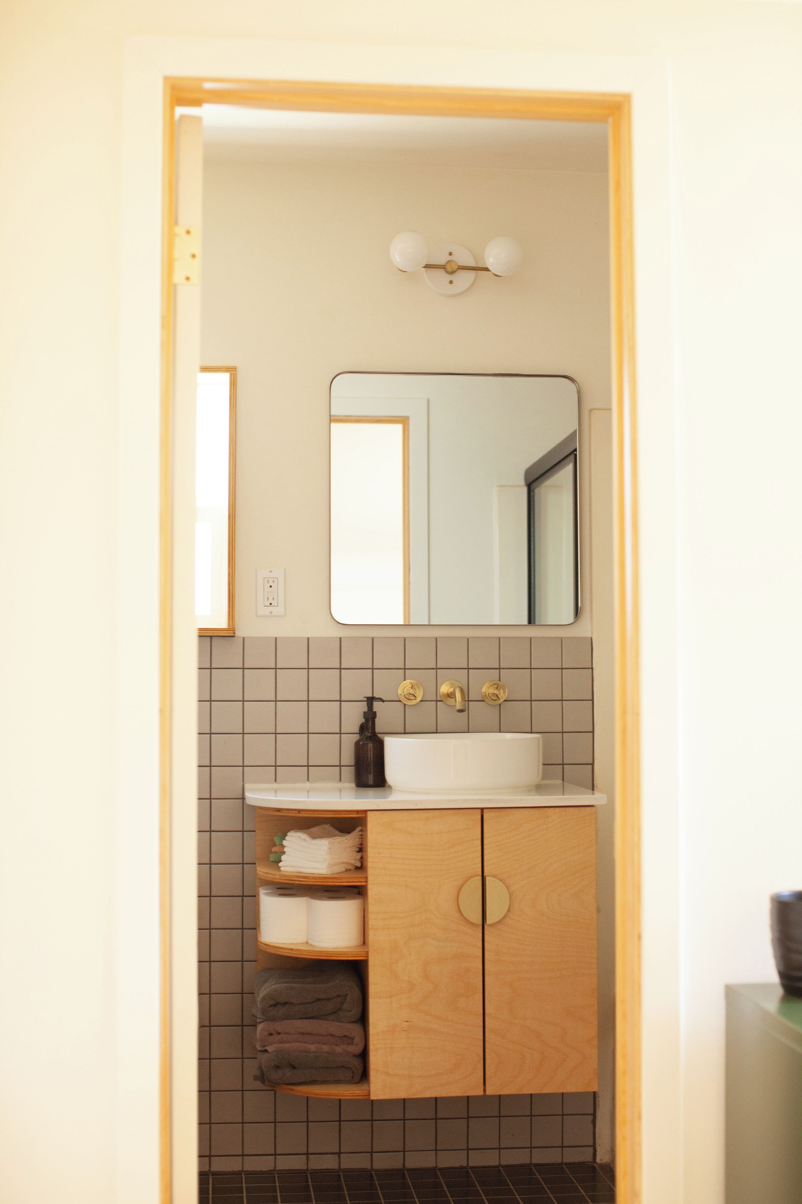 A bathroom with a wooden cabinet, a white sink, and a mirror above it.