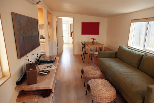 A spacious living area with a sofa, a dining table, and a kitchen in the background.