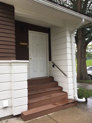 A residential house with a white front door, brown steps, and a white porch railing. - Tranquil 4-bedroom house 2 miles from ND (South Bend)