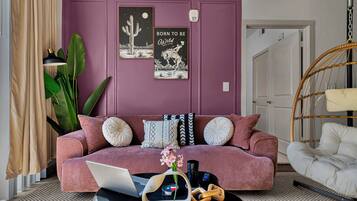 A living room with a purple wall, a sofa, a laptop, and a hanging chair.
