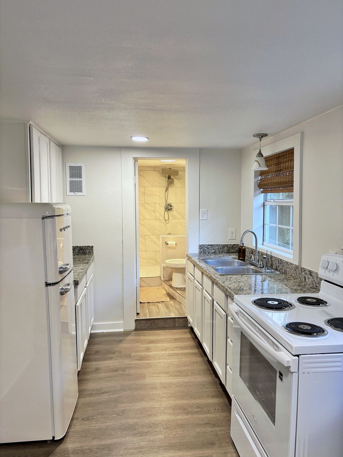A kitchen with white cabinets, a stove, and a sink.