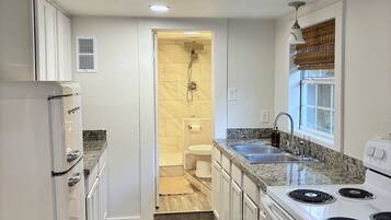 A kitchen with white cabinets, a stove, and a sink.
