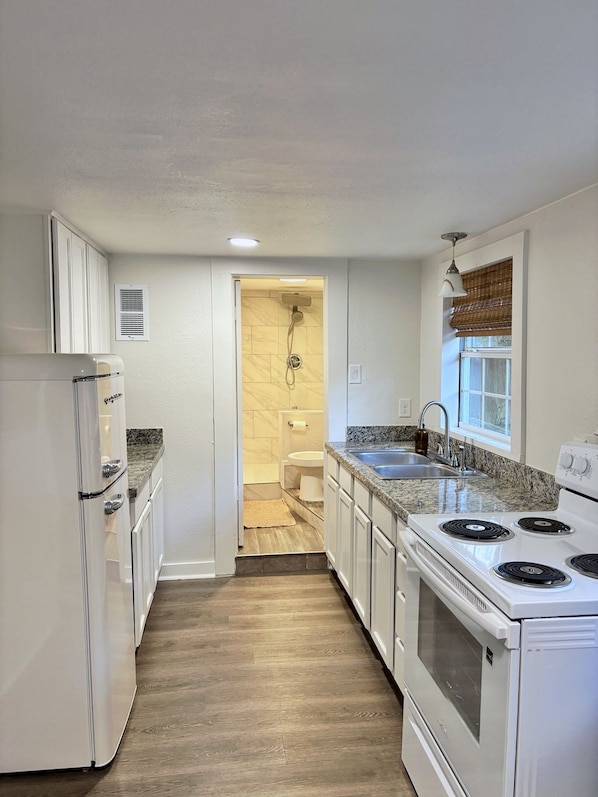A kitchen with white cabinets, a stove, and a sink.