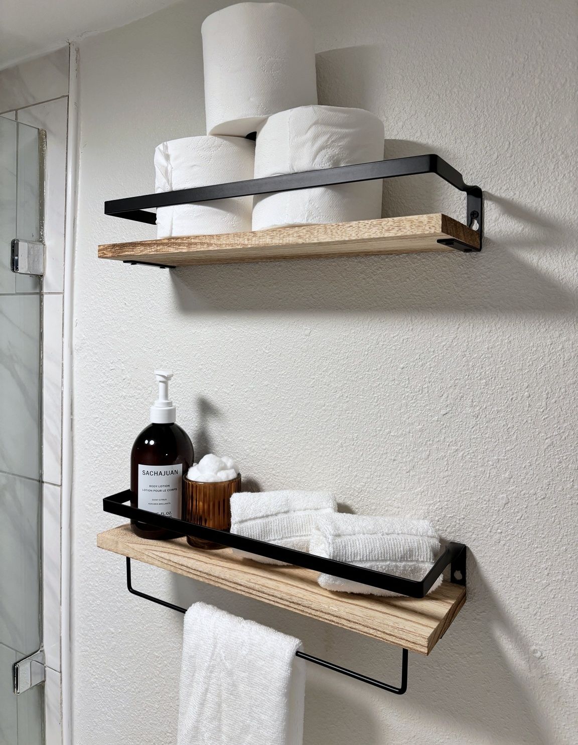 A bathroom with two wooden shelves mounted on the wall, holding toiletries and towels.