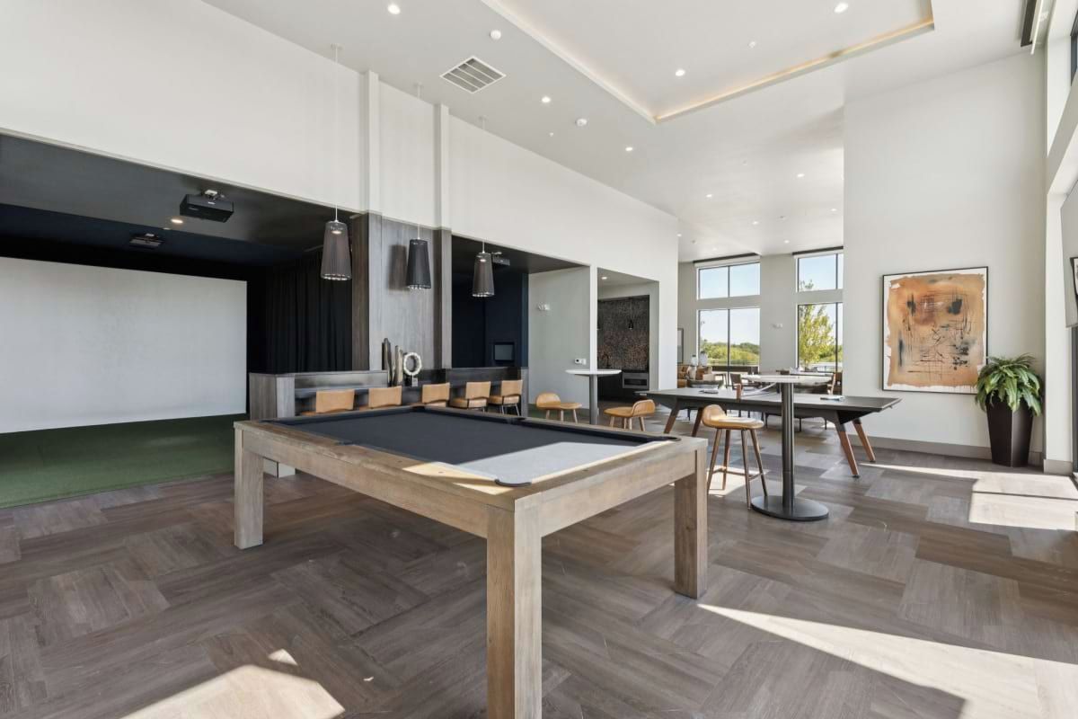 Un espace intérieur moderne doté d’une table de billard, d’un coin salon et de grandes fenêtres.