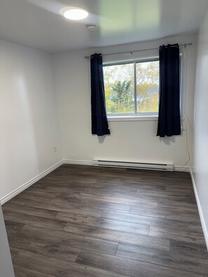 Een kamer met een groot raam, donkere gordijnen en een centrale verwarming.
