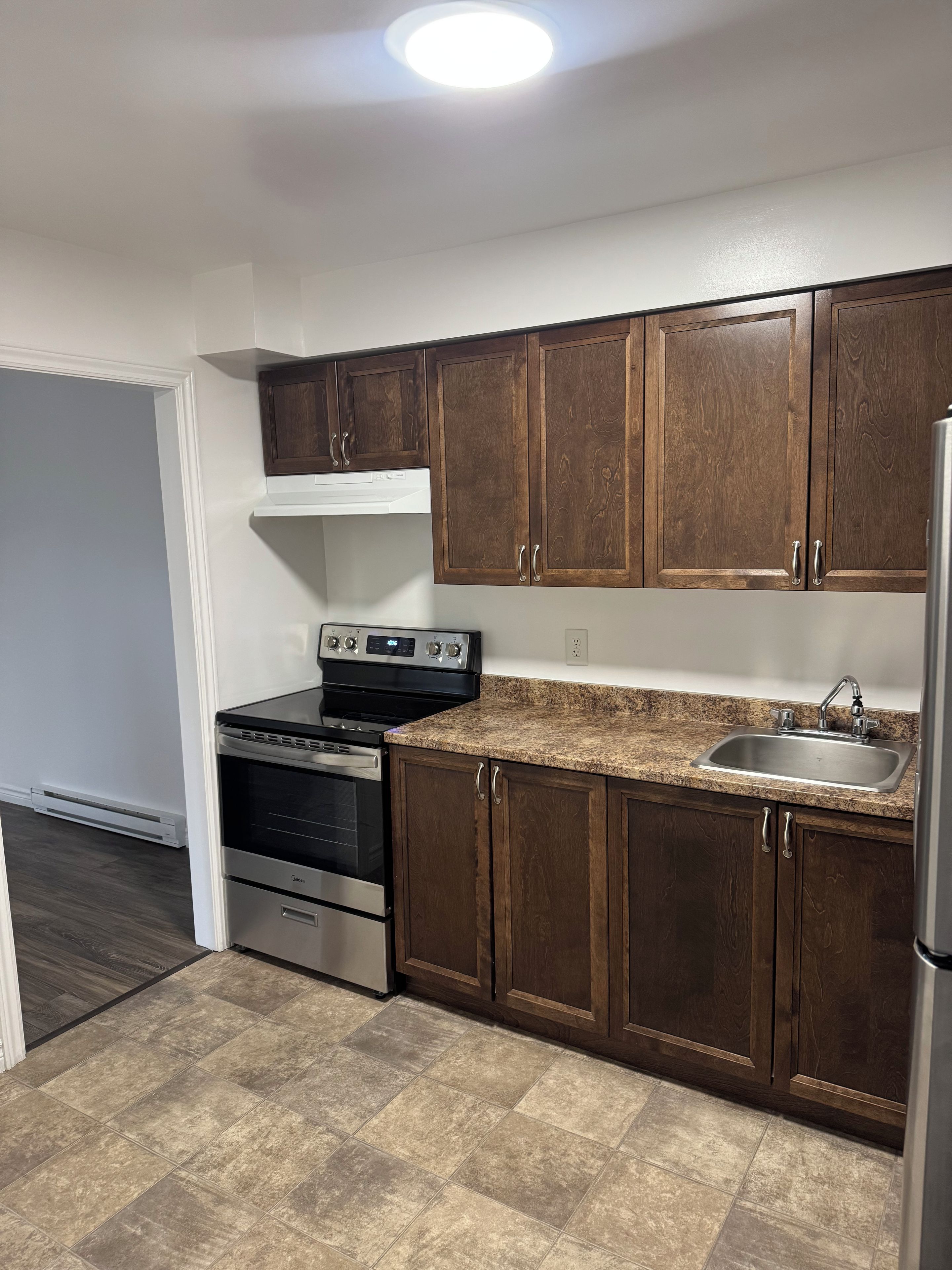 A kitchen with dark wooden cabinets, a stainless steel sink, and a built-in oven.