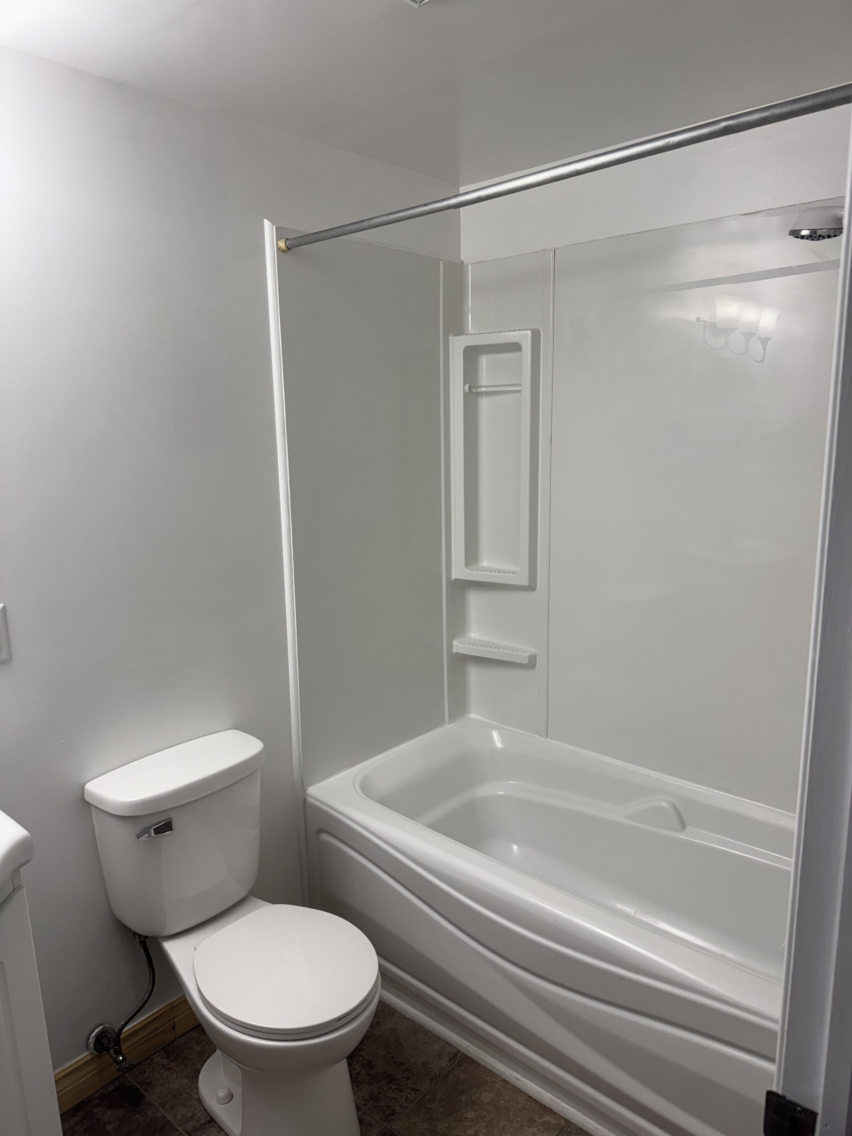 A bathroom with a toilet, a bathtub, and a shower enclosure.