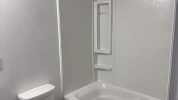 A bathroom with a toilet, a bathtub, and a shower enclosure.