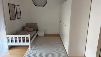 Ein Schlafzimmer mit Bett, Nachttisch, Kleiderschrank und einer Pendelleuchte.
