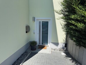 A narrow entrance with a door, a mailbox, a potted plant, and a welcome mat.