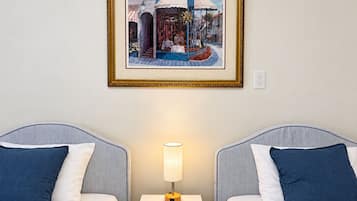 A hotel room with two beds, a nightstand, a lamp, and a framed picture on the wall.