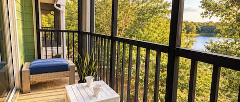 Ein Balkon mit Seeblick, einem weißen Tisch und einer blauen gepolsterten Bank.