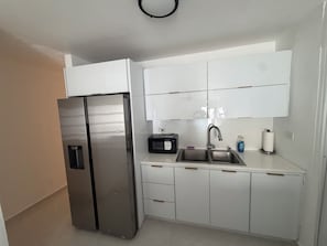 A kitchen with white cabinets, a stainless steel refrigerator, a microwave, and a sink with a faucet. - 2-bedroom apartment, living room, bathroom, with its own parking space (Toa baja)