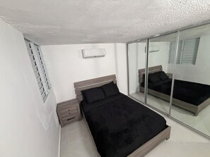 A bedroom with a bed, a nightstand, a mirror, and a window with blinds. - 2-bedroom apartment, living room, bathroom, with its own parking space (Toa baja)