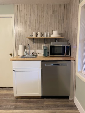 Eine kompakte Küche mit Geschirrspüler, Mikrowelle, Spüle und einer Holz Arbeitsplatte.
