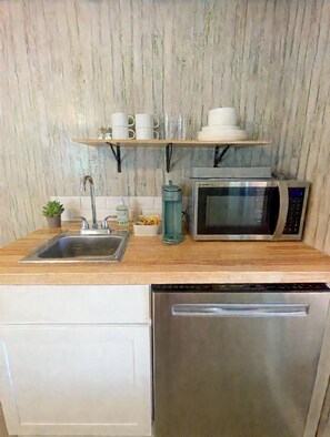 Una cocina funcional con lavabo, microondas y lavavajillas.