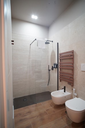 Een moderne badkamer met een douche, twee wasbakken en een handdoekhouder.