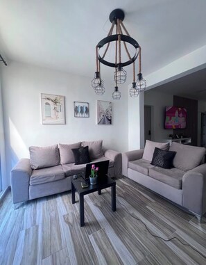 A modern living room with two sofas, a coffee table, and a chandelier. - Vrbo Property (Punta Cana)