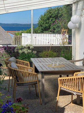 An outdoor patio with a table and chairs, surrounded by plants and a view of the sea. - Townhouse in historic Ebeltoft with sea view (Ebeltoft)