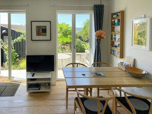 A room with a television, dining table, chairs, a bookshelf, and a view of the outdoors. - Townhouse in historic Ebeltoft with sea view (Ebeltoft)