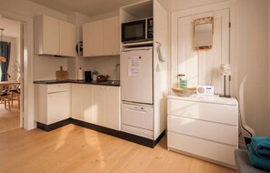 A compact kitchen with white cabinets, a microwave, a refrigerator, and a small sink. - Townhouse in historic Ebeltoft with sea view (Ebeltoft)