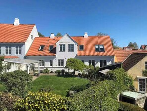 A residential building with a red-tiled roof, multiple windows, and a well-maintained lawn. - Townhouse in historic Ebeltoft with sea view (Ebeltoft)