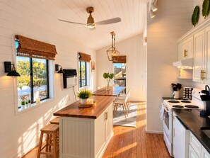 A kitchen with white cabinetry, a wooden island, and a ceiling fan.