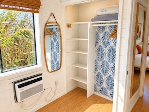 Una habitación con ventana, espejo, armario y radiador.