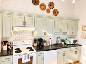 A kitchen with white cabinetry, a stove, a sink, and various kitchen appliances.