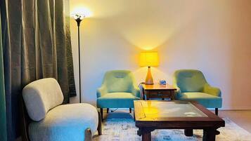 Een kamer met een bank, twee fauteuils, een salontafel, een lamp en een vloerlamp.