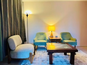 Una habitación con sofá, dos sillones, una mesita de centro, una lámpara y una lámpara de pie.