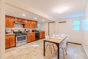 Una cocina moderna con armarios de madera, electrodomésticos de acero inoxidable y un comedor con mesa preparada para cuatro.