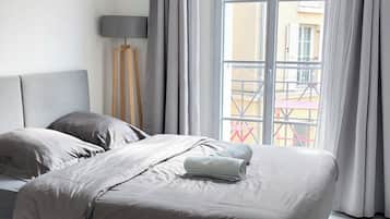 A modern bedroom with a bed, a standing lamp, and a view of a balcony.