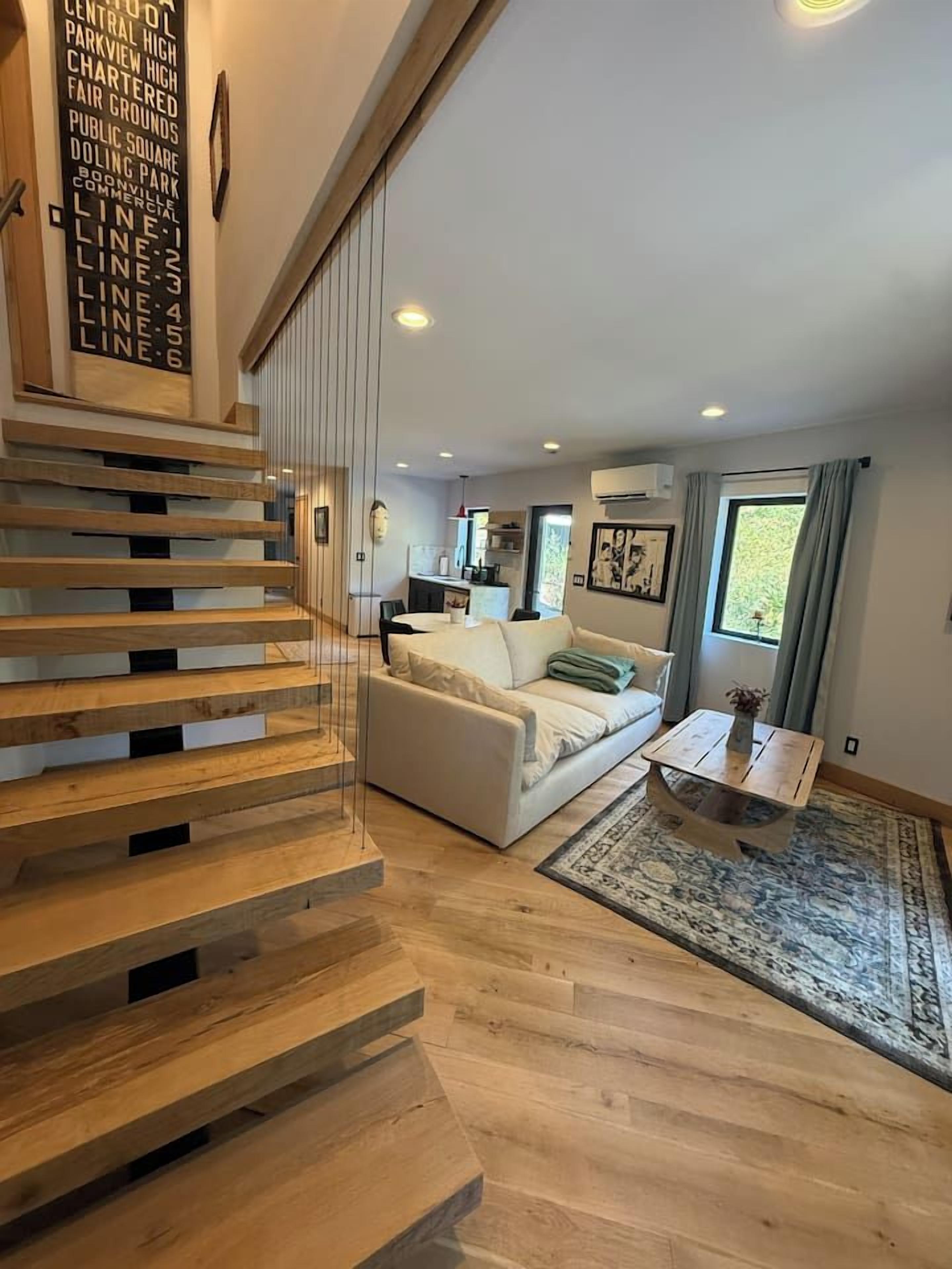 A modern interior with a wooden staircase, a white sofa, and a coffee table.