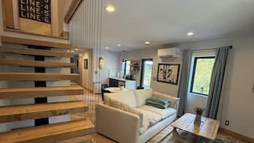 A modern interior with a wooden staircase, a white sofa, and a coffee table.
