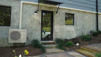 A modern house with a concrete exterior, a black door, and an air conditioning unit.