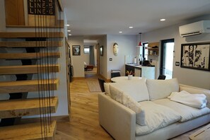 A modern interior with a staircase, a living area with a sofa, a kitchen, and a dining area. - The Oakley Art House (Chattanooga)