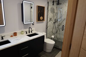 Ein modernes Badezimmer mit einem Doppelwaschbecken, einem Spiegel, einer Toilette und einer Duschkabine.