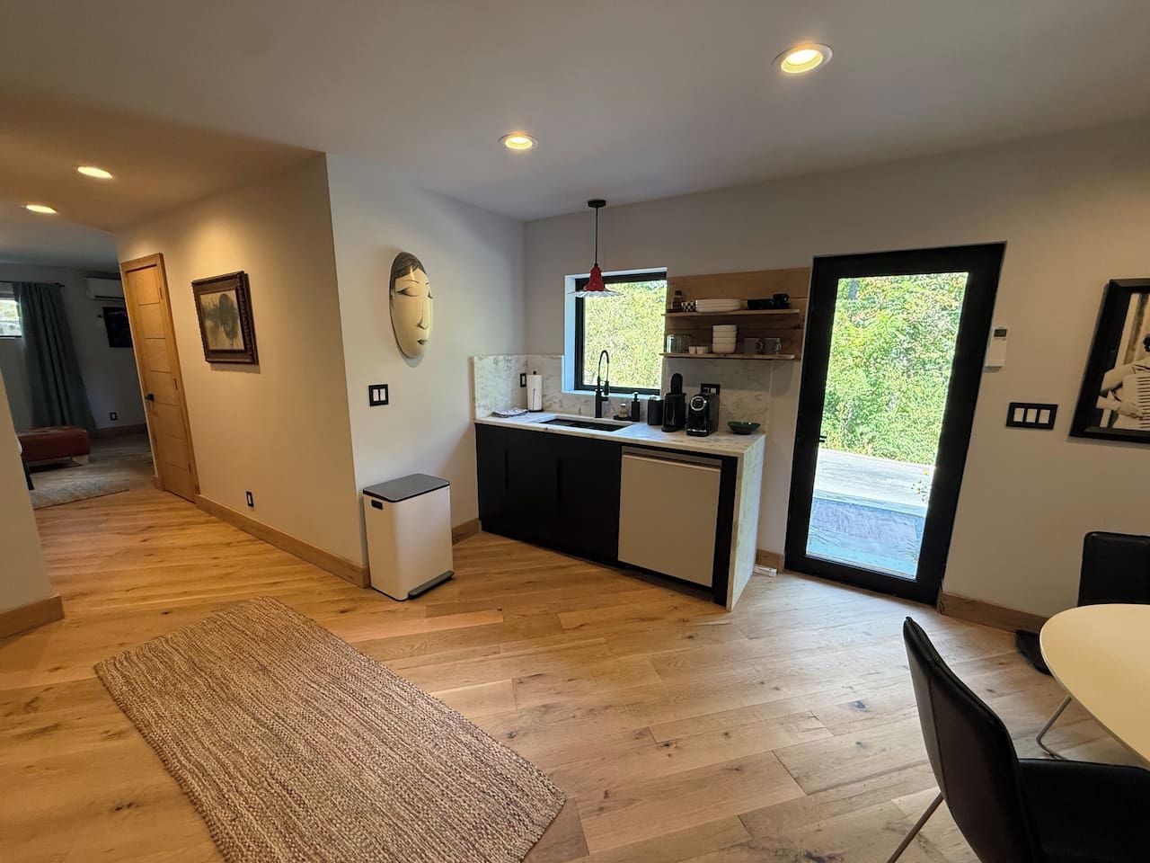 A modern kitchen with a central island, a dining area with a table and chairs, and a large sliding glass door leading to an outdoor area.